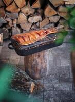 rökt fisk på en grill mot en bakgrund av ved. sommar picknick i de natur. matlagning mat på brand och i en utegrill. foto