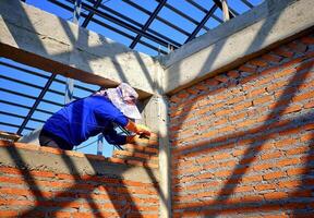 kvinna murare är arbetssätt till bygga tegel vägg strukturera i hus konstruktion webbplats foto