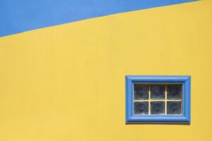 arkitektur bakgrund av små glas blockera fast fönster på färgrik blå och gul årgång byggnad vägg i minimal stil foto