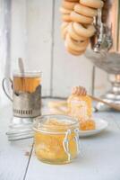 vaxkaka med honung i en burk och te från en ryska samovar med bagels, ekologiskt vitamin produkt som alternativ medicin foto