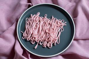 rosa tarama pasta på en grå tallrik pressas ut av en matlagning väska, kreativ textur foto