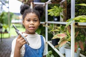 afrikansk amerikan unge innehav sekatör medan arbetssätt i henne trädgård efter skola för helgen aktivitet och utomhus- utbildning begrepp foto