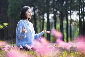 asiatisk kvinna är håller på med meditation mudra i de skog med vår Glödlampa blomma i blomning säsong för inre fred, mindfulness och zen öva foto