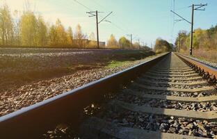 höst industriell landskap. järnväg avtagande in i de distans bland grön och gul höst träd foto