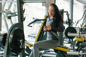 underbar ung kvinna textning och social nätverkande medan i en Gym. foto