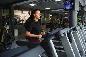 kvinna tåg på en löpband i de Gym. ung kondition flicka löpning på löpband maskin. sporter övningar för vikt förlust foto