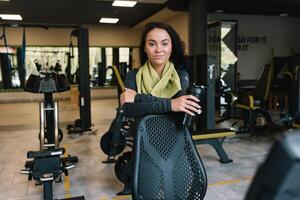 ung kvinna dricka vatten och tar en ha sönder efter träna i Gym foto