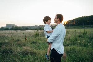 stilig pappa med hans liten söt son är har roligt och spelar på grön gräs- gräsmatta. Lycklig familj begrepp. skönhet natur scen med familj utomhus- livsstil. familj vilar tillsammans. fäder dag. foto