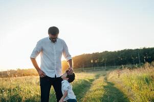 stilig pappa med hans liten söt son är har roligt och spelar på grön gräs- gräsmatta. Lycklig familj begrepp. skönhet natur scen med familj utomhus- livsstil. familj vilar tillsammans. fäder dag. foto