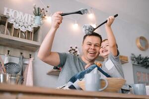ung man och hans son med ugn ark i kök. far med liten son på de kök. foto