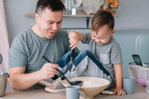 ung man och hans son med ugn ark i kök. far med liten son på de kök foto