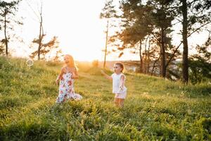 liten systrar flickor har roligt i de sommar skog, Sammanträde på de filt och leende foto