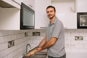 man skärande färsk fisk i kök i Hem. man slakt fisk för laga mat. foto