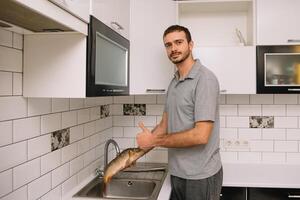 man skärande färsk fisk i kök i Hem. man slakt fisk för laga mat. foto