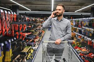 manlig byggare i en hårdvara Lagra väljer en verktyg foto