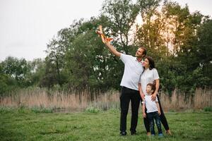 far, mor och son spelar med leksak flygplan i de parkera. vänlig familj. människor har roligt utomhus. bild tillverkad på de bakgrund av de parkera och blå himmel. begrepp av en Lycklig familj foto