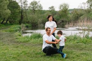 Lycklig familj mor far och barn son på natur på solnedgång. mamma, pappa och unge skrattande och kramar, njuter natur utanför. solig dag, Bra humör. begrepp av en Lycklig familj. foto