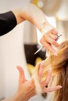 skärande kvinna blond hår. frisör nedskärningar hår av en ung caucasian kvinna i en skönhet salong stänga upp. foto