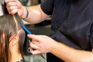 frisör delar upp kvinna hår in i sektioner med hårkam innehav hår med henne händer i hår salong stänga upp. foto