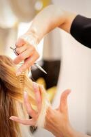 skärande kvinna blond hår. frisör nedskärningar hår av en ung caucasian kvinna i en skönhet salong stänga upp. foto