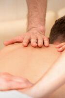 ung man tar emot tillbaka massage i fyra händer i spa skönhet salong. foto
