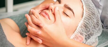 en ung caucasian kvinna få ansiktsbehandling massage i en spa. foto