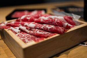 premie sällsynt skivor wagyu nötkött på fyrkant trä- tallrik eras för sukiyaki och shabu. foto