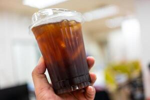 iced svart kaffe eller americano blandning i plast kopp i hand foto