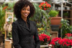 svart företag kvinna i en trädgård Centrum omgiven förbi grönska foto