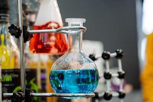 glas flaska med en blå sammansättning i en kemisk laboratorium, de studie av de samspel av olika petrokemiska element, vetenskap på de universitet. foto
