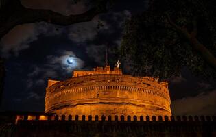 natt se genom de grenar av en träd av de castel sant'angelo fästning foto