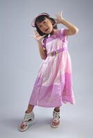 ett indonesiska liten flicka bär modern klänning med modellering utgör. foto