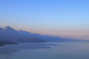 lugn marinmålning med avlägsen berg räckvidd, klar blå himmel, och lugn atmosfär. foto