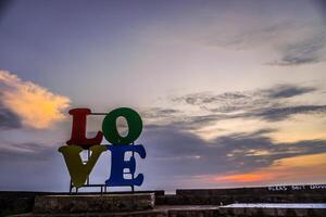 närbild se av de ord kärlek placerad på de kustlinje mot en solnedgång himmel med tömma Plats för fotokopiering. foto