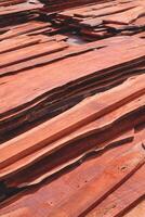 stack av många redwood trä paneler lugg på industriell gård i vertikal ram, trä konstruktion material bakgrund foto