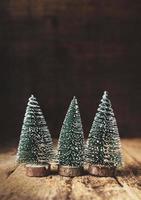 tre mini julgran trä på rustikt träbord och lövträ foto