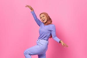 porträtt av vacker ung asiatisk kvinna som dansar glad och glad på rosa bakgrund