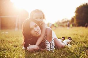 glad mor och dotter kramas i en park i solen på en ljus sommarbakgrund av örter. foto