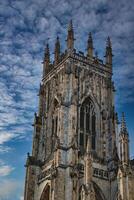 gotik katedral torn mot en dramatisk molnig himmel, visa upp invecklad arkitektonisk detaljer och spiror, idealisk för historisk eller religiös teman i york, norr yorkshire, england. foto