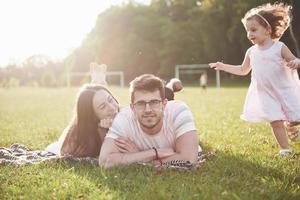 lycklig familj, far till mor och dotter till baby i naturen vid solnedgången foto