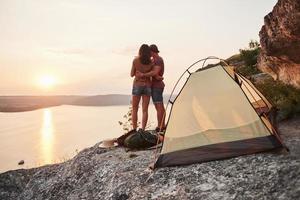 foto av glad nära tält med utsikt över sjön under vandringstur. resa livsstil äventyr semester koncept