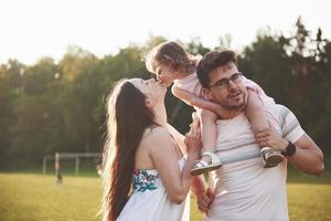 lycklig familj, far till mor och dotter till baby i naturen vid solnedgången foto