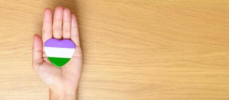 queer stolthet dag och HBTQ stolthet månad begrepp. hand innehav lila, vit och grön hjärta form för lesbisk, Gay, bisexuell, transpersoner, genderqueer och pansexual gemenskap foto