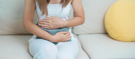 menstruation period cykel av en gång i månaden och magont begrepp. kvinna har buk smärta och menstruations- värk med varm vatten flaska, sjukdom kvinna lida från premenstruell värk och kropp hälsa problem foto