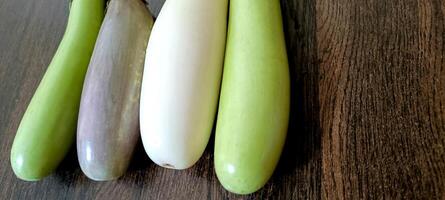 närbild av organisk vit och grön färsk äggplanta eller brinjal isolerat på trä- bakgrund foto