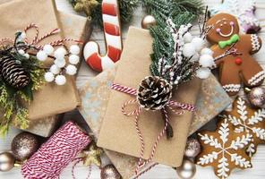 snygga rustika julklappar med tall grenar och dekoration på bakgrund av gyllene grannlåt, kottar, pepparkakor.