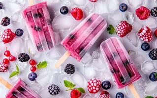 frysta is popsicles av mjölk och bär över rosa bakgrund. färsk frukt is grädde friska mat. foto