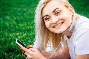 kvinna i hörlurar och smartphone i händerna lyssnar på musik foto