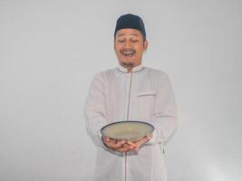 moslem asiatisk man leende Lycklig medan innehav tömma middag tallrik foto