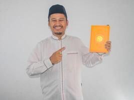 moslem asiatisk man leende medan pekande till en bok den där han håll foto